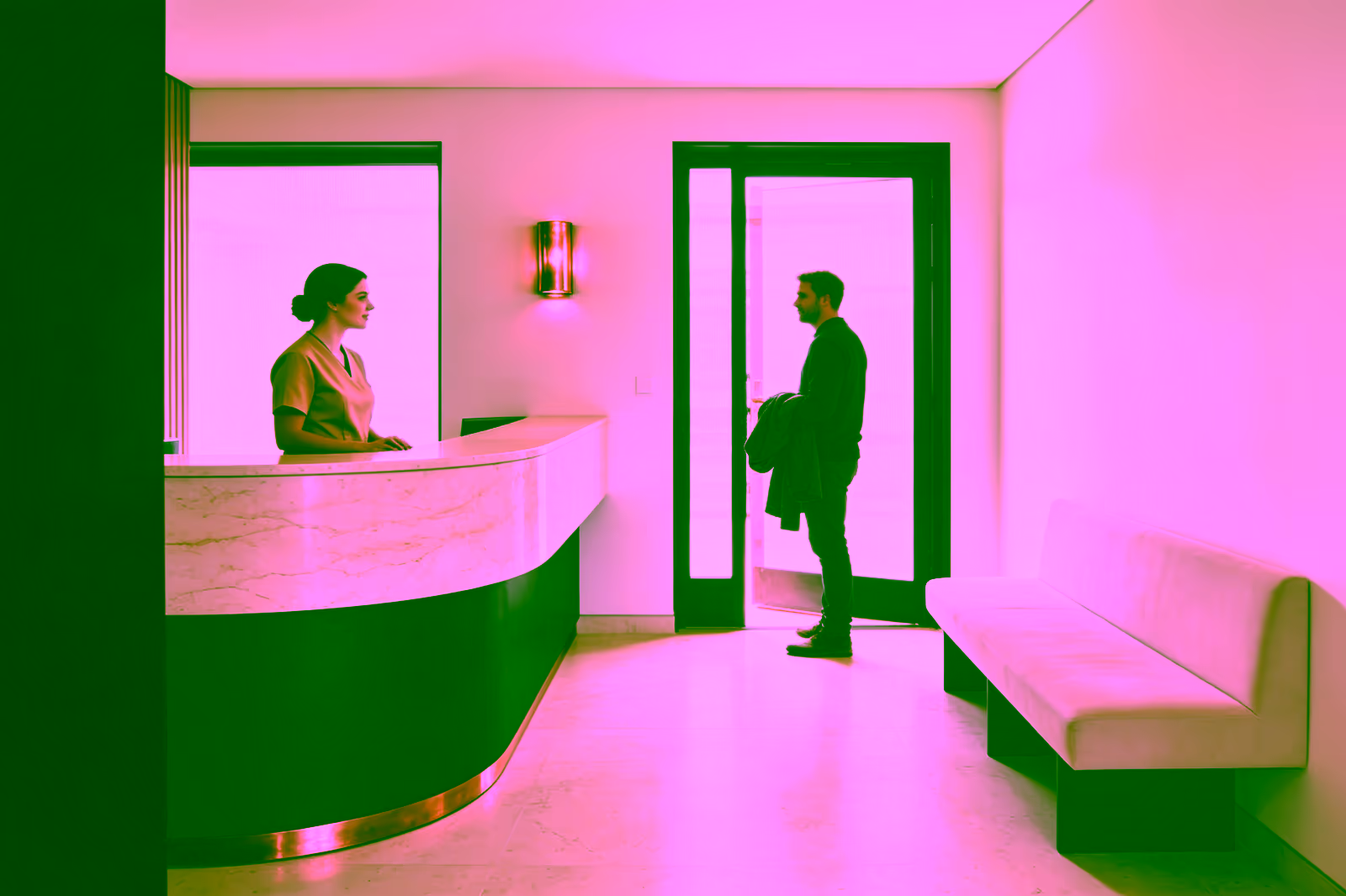 Una recepcionista da la bienvenida a un paciente en el mostrador de un consultorio.